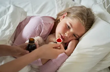 Podawanie chorej dziewczynce syropu do picia