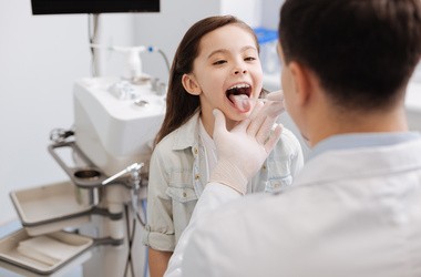 Mała pacjentka wystawiająca język u lekarza podczas badania