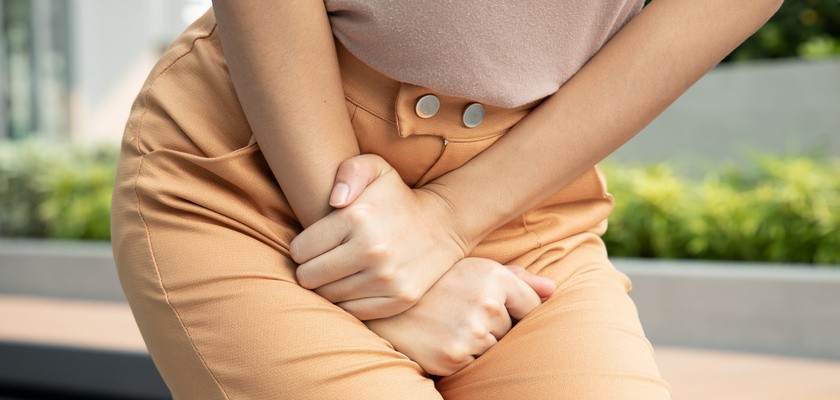 Kobieta trzyma ręce poniżej swojego brzucha. Problem z infekcją dróg moczowych.