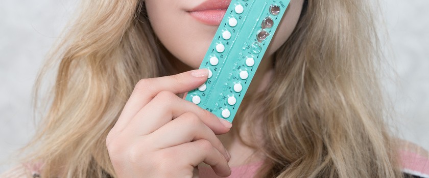 Dziewczyna trzyma w dłoni doustne środki antykoncepcyjne.