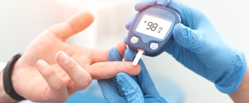 Doktor sprawdza poziom cukru we krwi za pomocą glukometru.