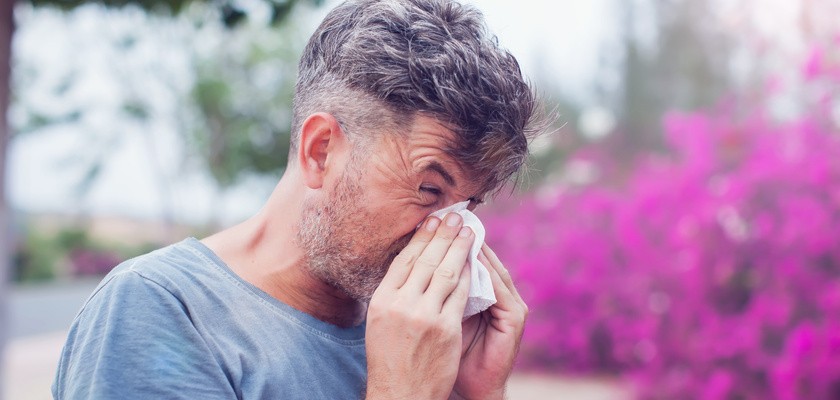 Mężczyzna opróżniający nos w chusteczkę z powodu kataru siennego.