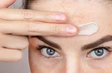 Kobieta smaruje przebarwienia na czole kremem z niacynamidem. Na co niacynamid, niacynamid zastosowanie