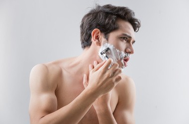 Mężczyzna w piance do golenia goli sobie zarost