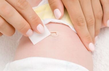 Kobiece dłonie czyszczące okolice pępka noworodka. Wydzielina z pępka.