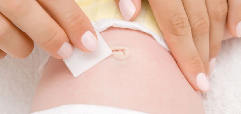 Kobiece dłonie czyszczące okolice pępka noworodka. Wydzielina z pępka.