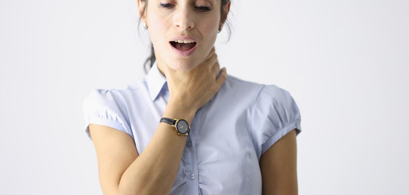 Kobieta trzymająca się za gardło podczas mówienia