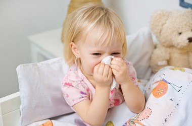 Mała dziewczynka wydmuchuje nos w chusteczkę