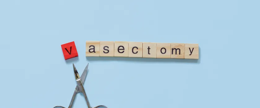 Ułożony napis "Vasectomy" z literek do Scrable na błękitnym tle. Poniżej nożyczki.