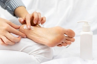 kobieta nakładająca krem na popękane pięty