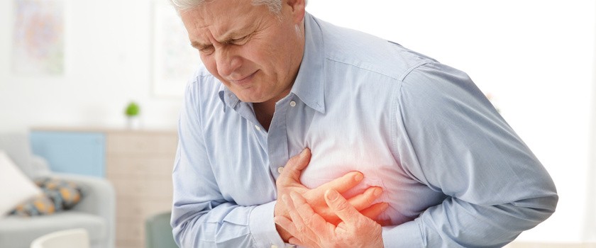 Starszy mężczyzna trzymający się za klatkę piersiową w okolicy serca.