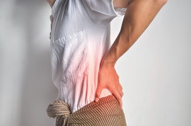 Mężczyzna trzyma się z tyłu na plecach. Może to być bólem związanym z kamieniami nerkowymi.