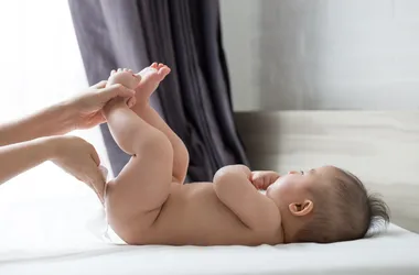 Mama przemywa pupę niemowlakowi