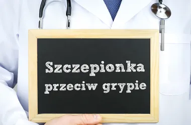 Lekarz w kitlu oraz z stetoskopem trzymający tablice z napisem "Szczepionka przeciw grypie".