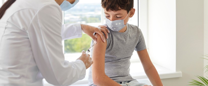 Pani doktor robiąca zastrzyk chłopcowi wraz ze szczepionką na choroby zakaźne.