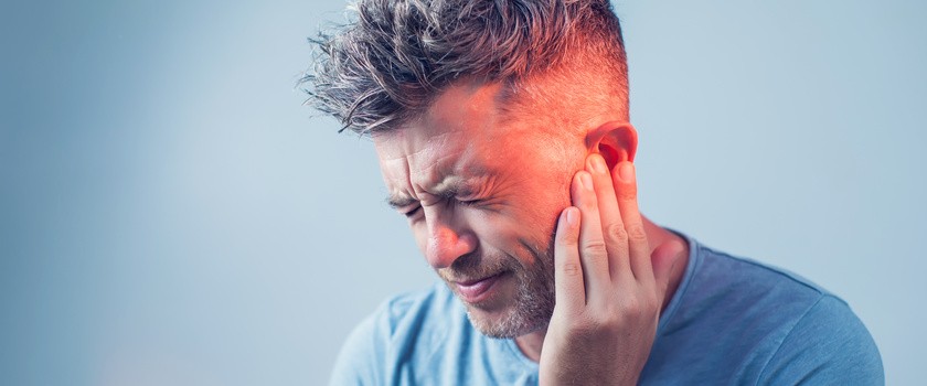 Mężczyzna trzymający się za ucho z powodu bólu