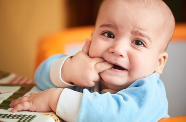 Płaczący chłopiec i gryzący swoje palce z powodu ząbkowania