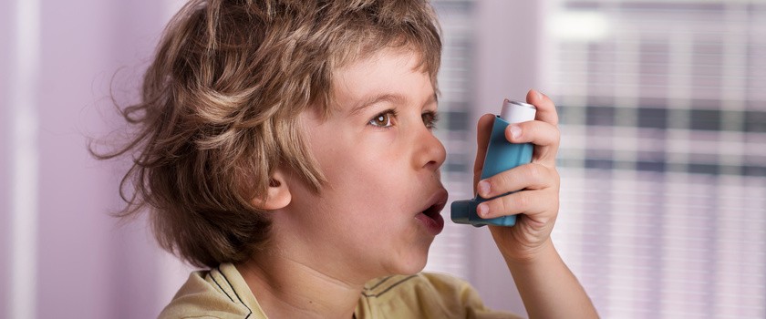 Chłopiec używający inhalatora z powodu duszności.