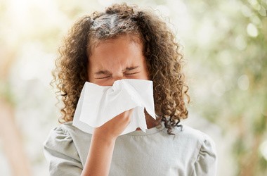 Chora mała dziewczynka wydmuchuje nos. Dziecko cierpiące na zatoki lub alergie.