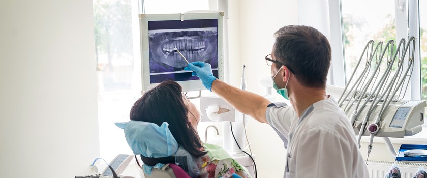 Lekarz dentysta pokazuje zęby pacjenta na zdjęciu rentgenowskim