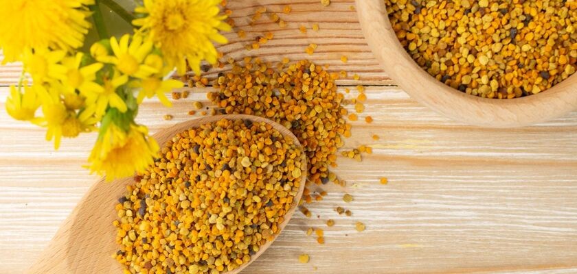 Pyłek pszczeli na drewnianej łyżce, kwiaty. Pyłek kwiatowy.