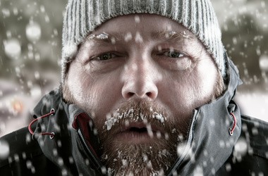 Zmarznięty mężczyzna w czapce podczas opadów śniegu.