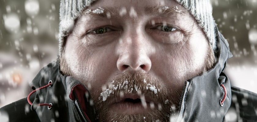 Zmarznięty mężczyzna w czapce podczas opadów śniegu.