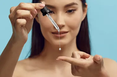 Ładna kobieta wraz z pipetą z serum zawierające retinol.