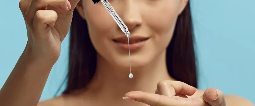 Ładna kobieta wraz z pipetą z serum zawierające retinol.
