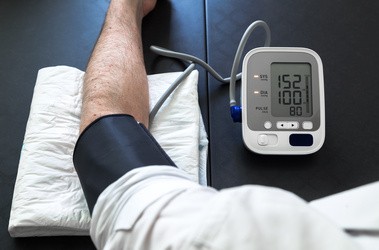 Pacjent z nadciśnieniem wykonujący samokontrolę ciśnienia krwi przez mężczyznę za pomocą tensjometru.