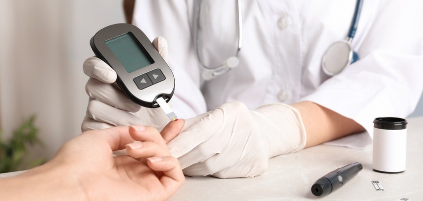 lekarz sprawdzający poziom cukru we krwi pacjenta za pomocą glukometru w gabinecie