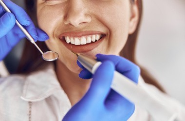 Lekarz wykonuje ultradźwiękowe czyszczenie kamienia w nowoczesnym gabinecie dentystycznym.