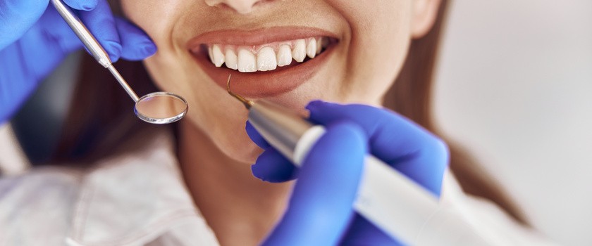 Lekarz wykonuje ultradźwiękowe czyszczenie kamienia w nowoczesnym gabinecie dentystycznym.