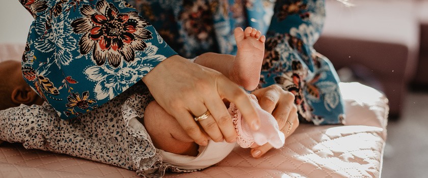 Kobieta w sukience przewija niemowlaka