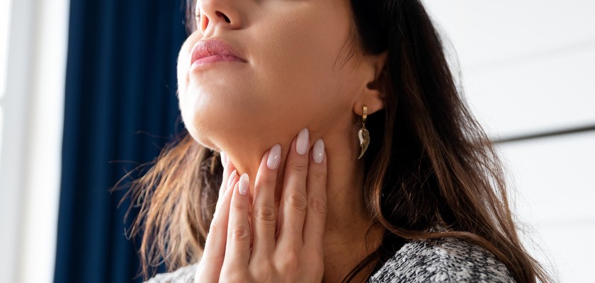 Młoda kobieta wykonująca sobie badanie tarczycy.