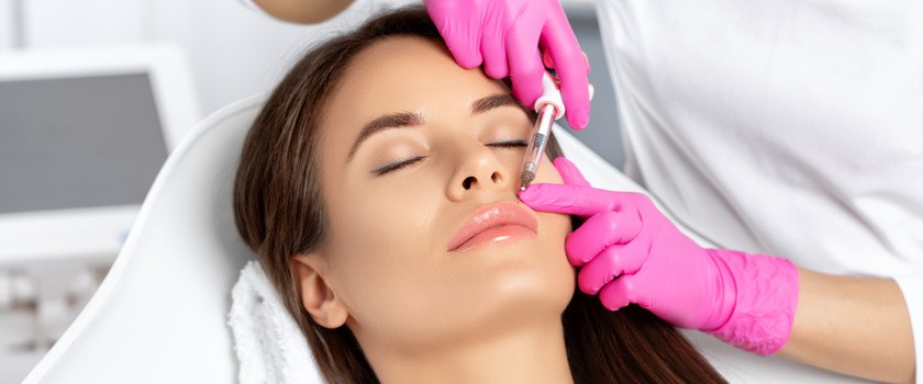 Kobieta z piękną czystą skórą w salonie kosmetycznym poddaje się zabiegowi. Kosmetolog robi zastrzyk na powiększanie ust pięknej kobiet