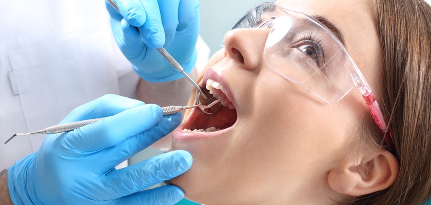 Stomatolog przeprowadza przegląd uzębienia u pacjentki w celu wykrycia ognisk próchnicy