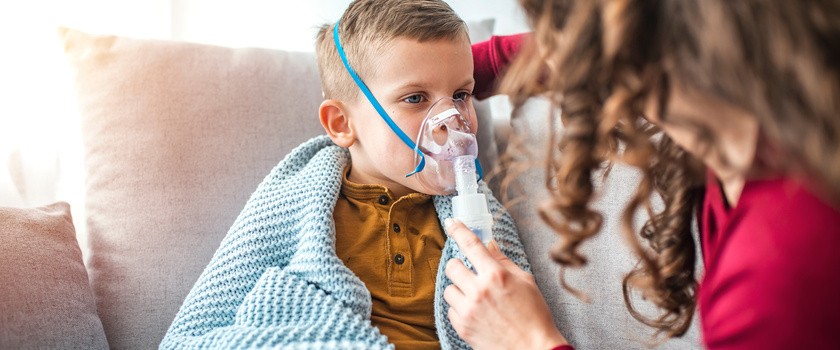 Kobieta z synem robi inhalację z nebulizatorem w domu. Dziecko cierpiące na choroby układu oddechowego.