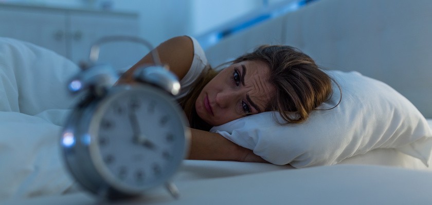 Kobieta z bezsennością leżąca w łóżku z otworzonymi oczami i zastanawiająca się, dlaczego nie może zasnąć.