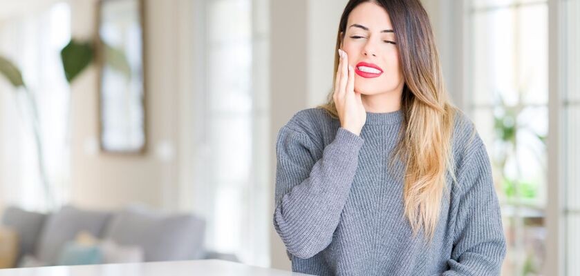 Kobieta trzymająca się za żuchwę. Antybiotyki na zęby, jak działają antybiotyki stomatologiczne?
