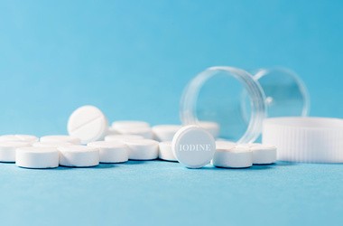 Rozsypane tabletki ze słoika na błękitnym tle