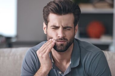 Mężczyzna trzymający się za policzek. Opuchlizna od zęba, obrzęk od zęba. 