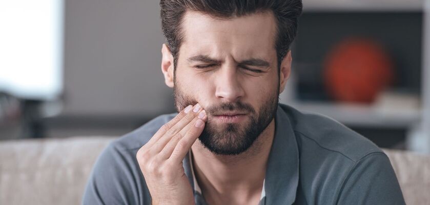 Mężczyzna trzymający się za policzek. Opuchlizna od zęba, obrzęk od zęba. 