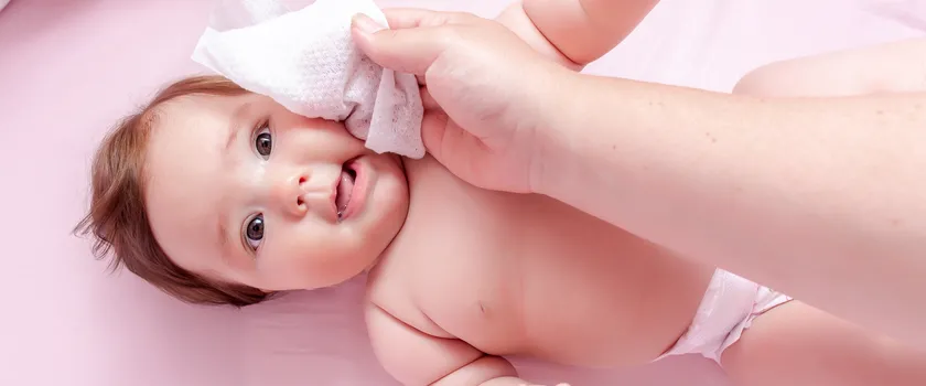 Osoba dorosła przeciera niemowlaka chusteczkę nawilżaną.
