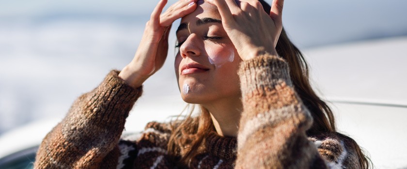 Kobieta smarująca kremem swoją twarz w zimę
