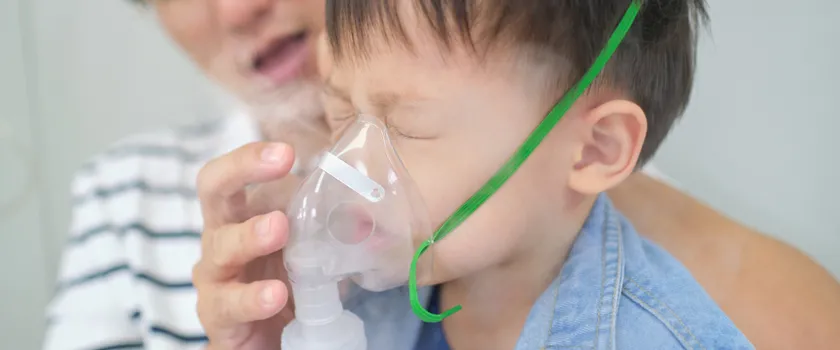 rodzic pomaga małemu dziecku z zamkniętymi oczami i maską na twarzy podczas inhalacji z soli