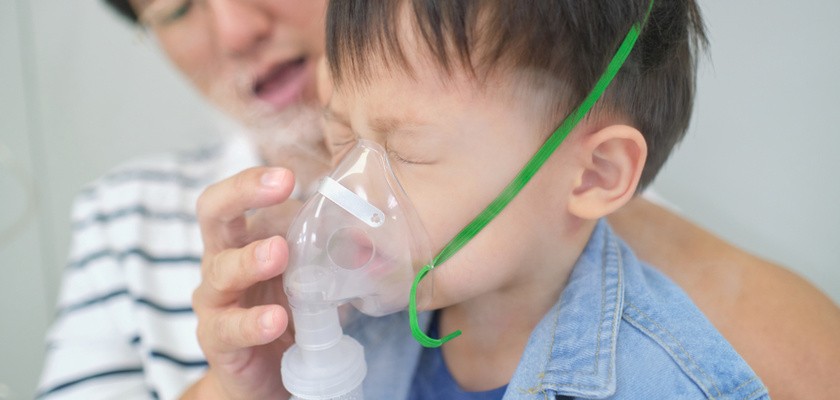rodzic pomaga małemu dziecku z zamkniętymi oczami i maską na twarzy podczas inhalacji z soli